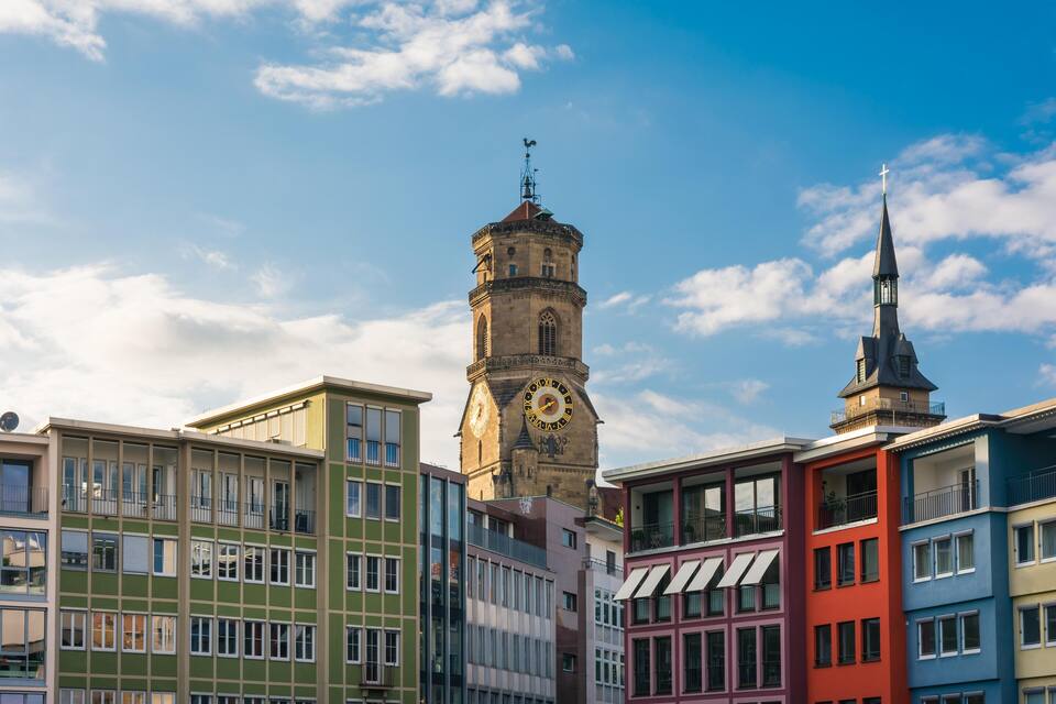 A historic clock tower and a church steeple against a clear sky.