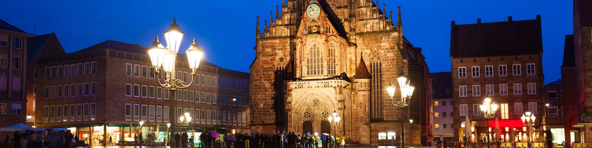 Una catedral histórica con una torre de reloj, una plaza adoquinada y edificios circundantes.