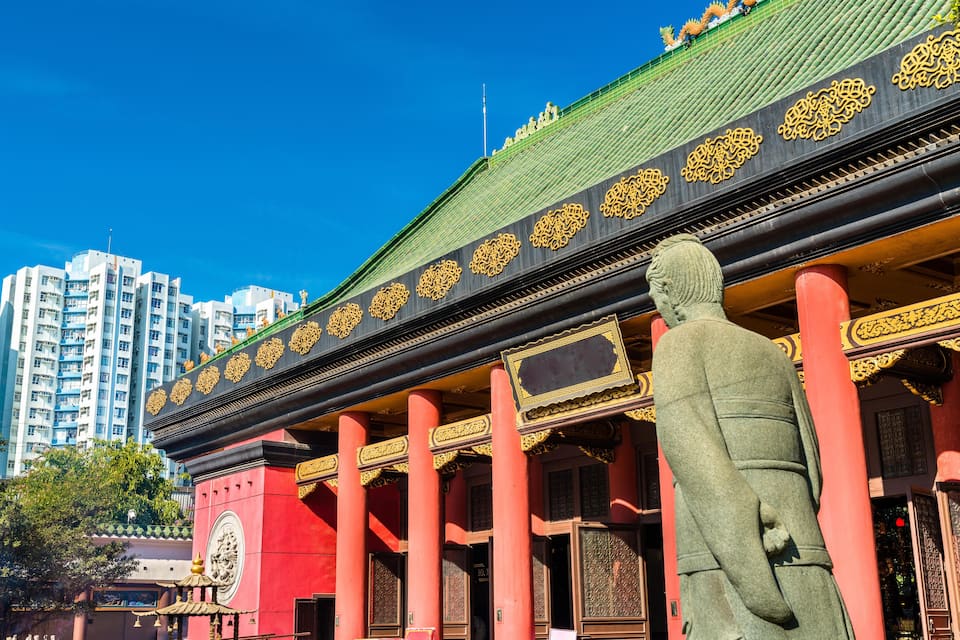 A traditional building with ornate golden decorations and a large statue in front.