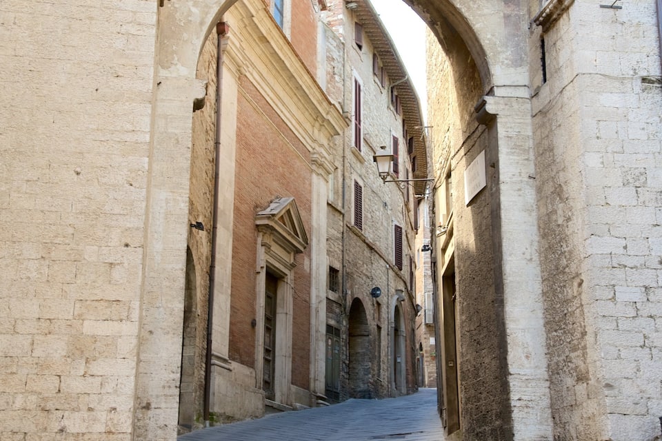 A narrow street flanked by historic buildings with arched doorways and a cobblestone path.