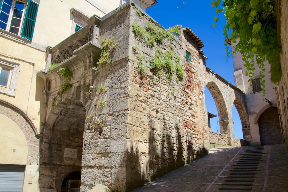 A narrow street with stone buildings, a staircase, and an arched bridge.