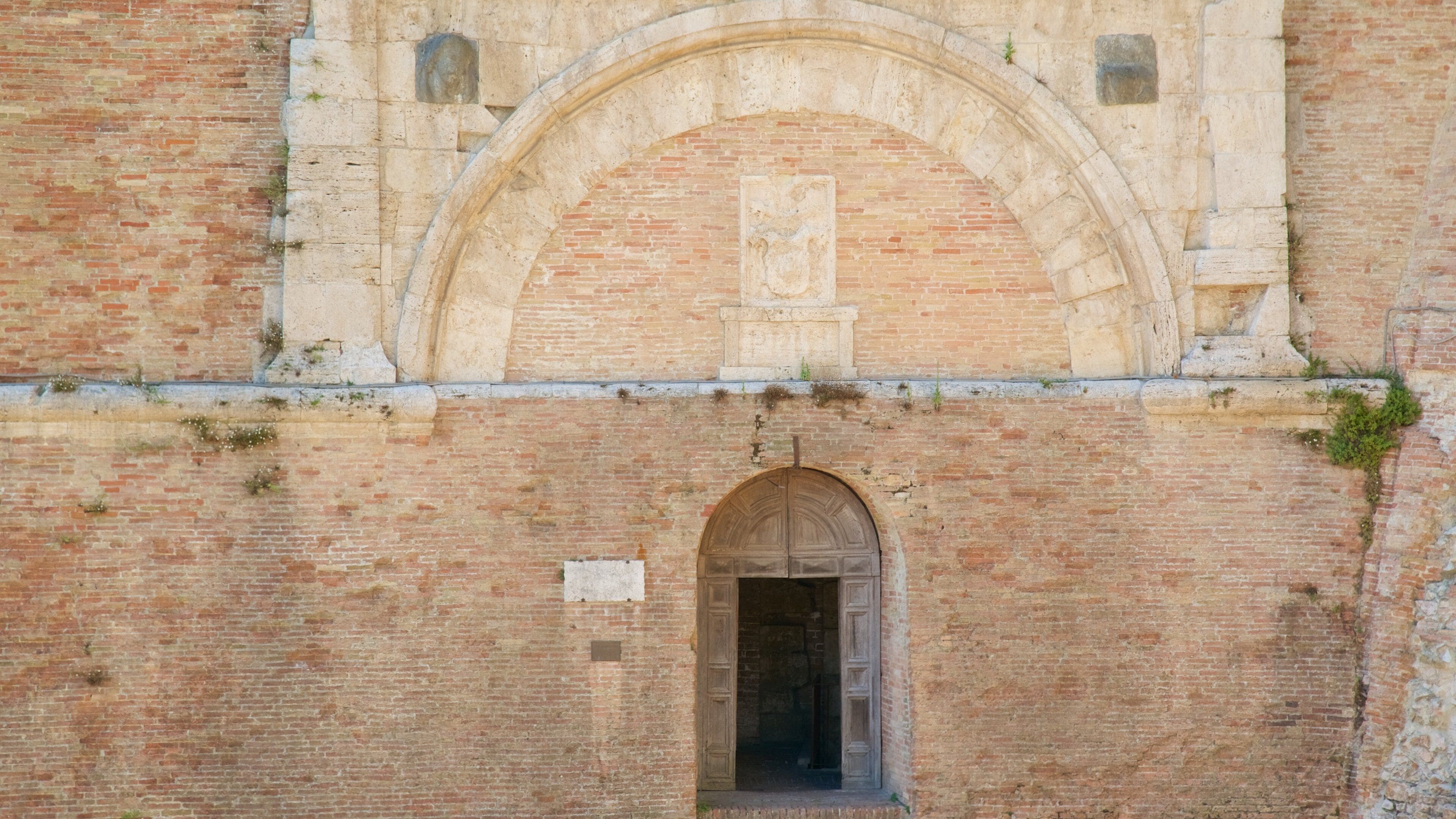 An old brick building with a large arched entrance and a smaller arched window above it.