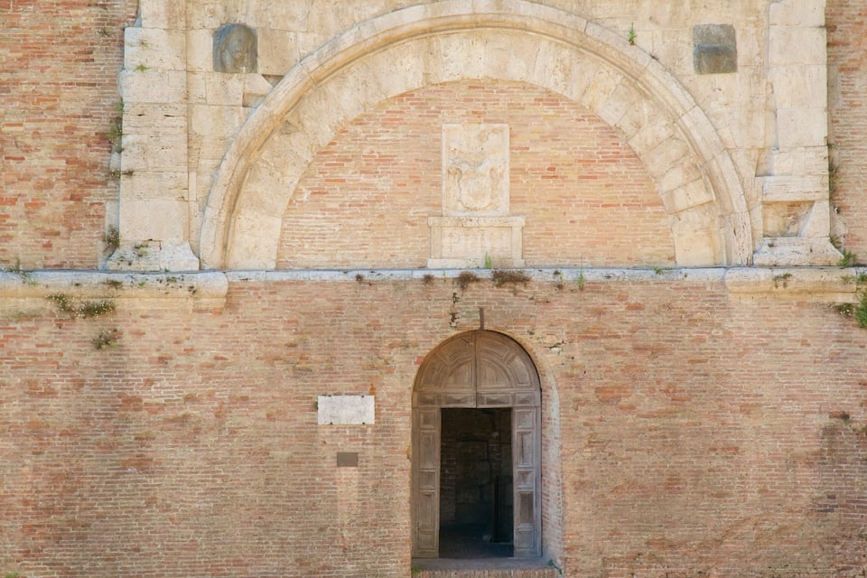 An old brick building with a large arched entrance and a smaller arched window above it.