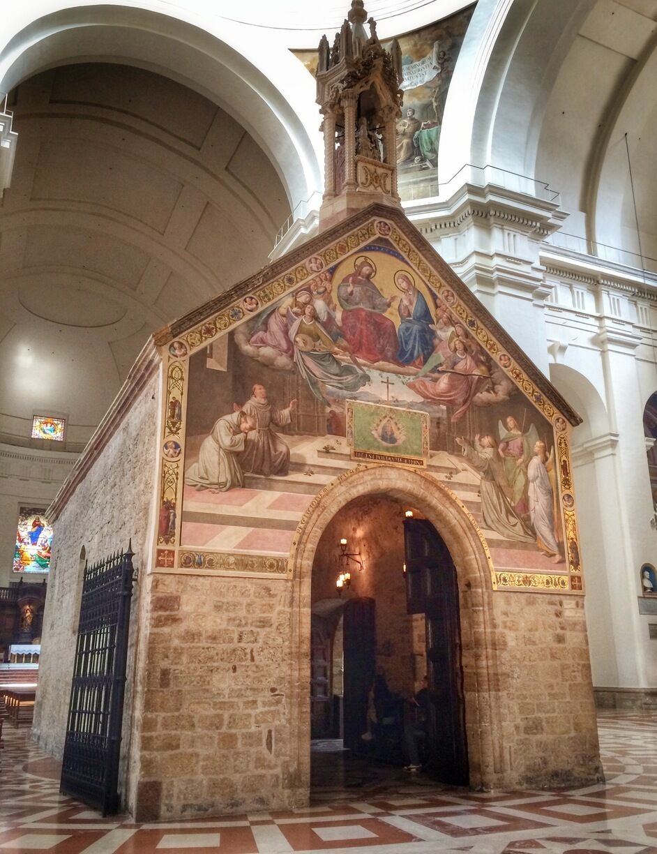 A church interior with a detailed fresco mural, stone architecture, and a checkered floor pattern.