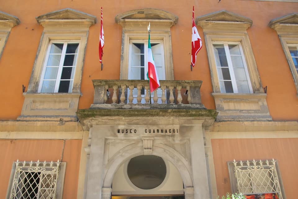 A building with a balcony, windows, and flags.