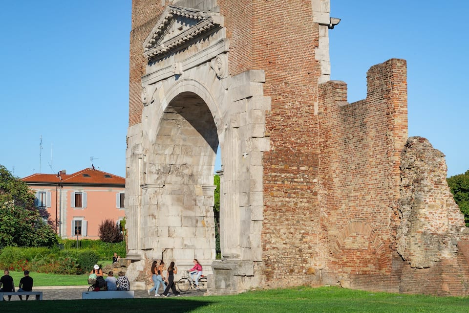 An ancient stone archway with a brick structure behind it.