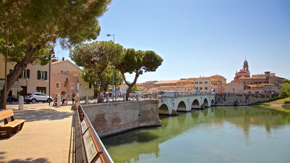 Un pont de pierre historique enjambant une rivière paisible, entouré d’arbres et de bâtiments traditionnels.