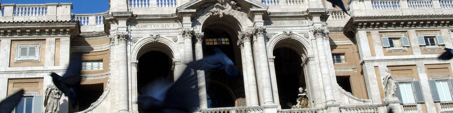 Italy, Rome, pigeons flying in front of Santa Maria Maggiore