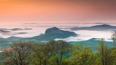 Gorgeous panoramic photo of Looking Glass Rock in Pisgah National Forest surrounding by early morning fog.