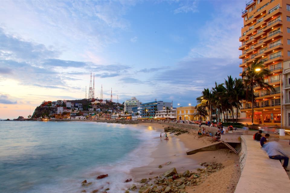A coastal cityscape with a beach, palm trees, and a prominent hotel building.