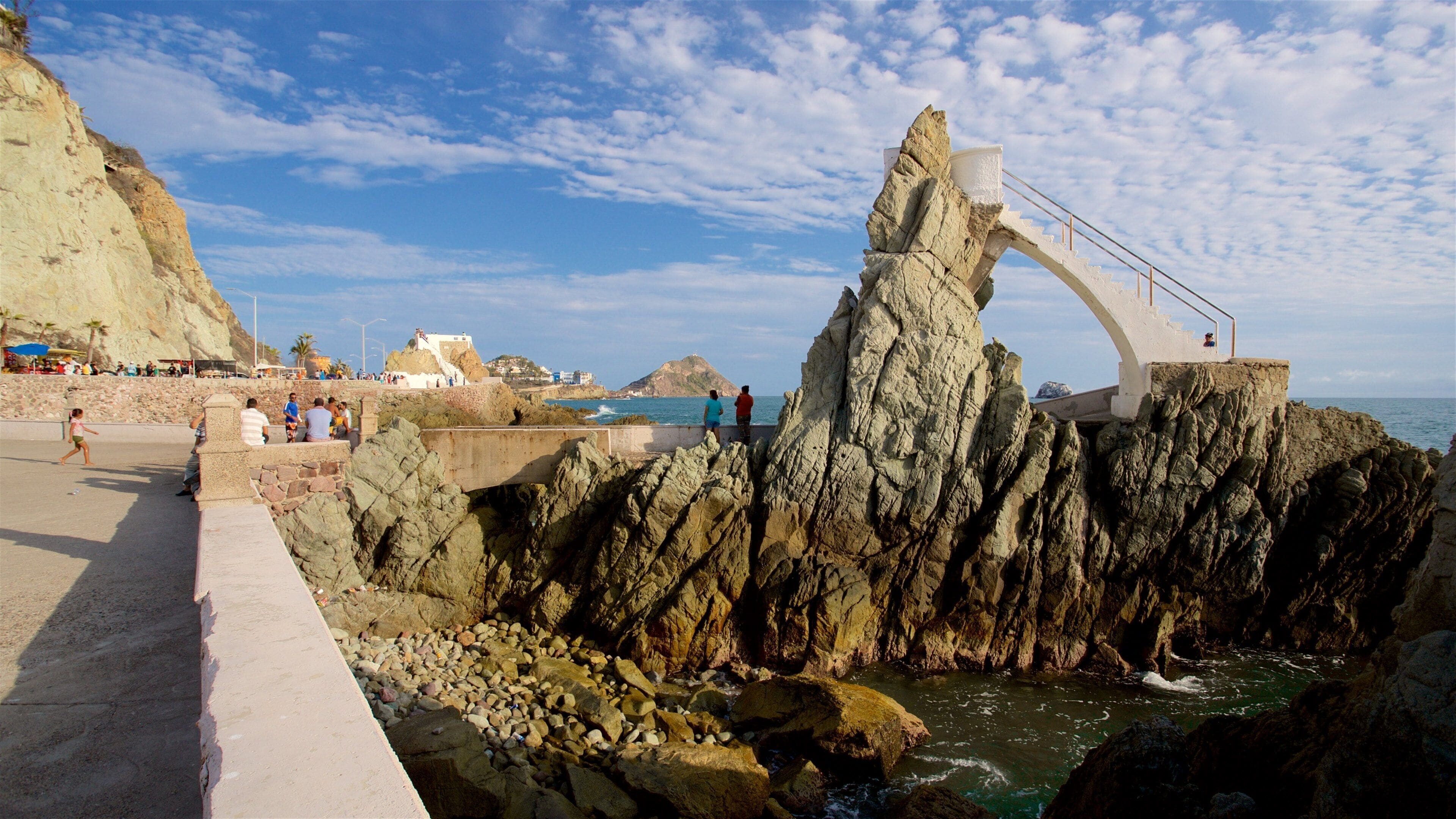 A rocky coastal area with a white arch structure overlooking the sea.