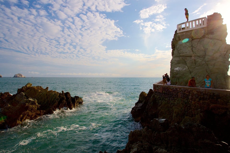 A rocky coastline with a sea wall and a person standing on top.