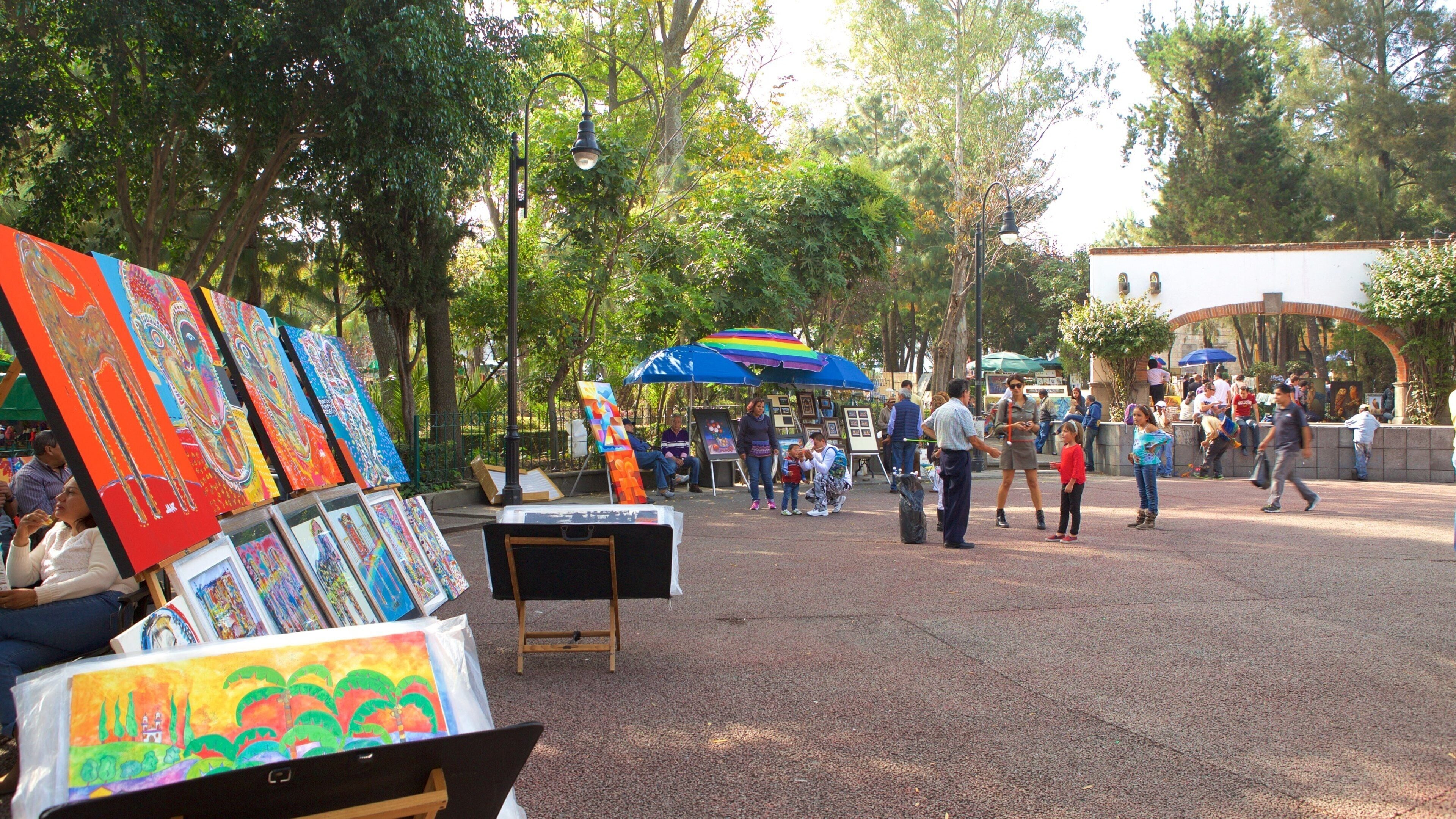 A vibrant outdoor art market with colorful paintings and a crowd of people.