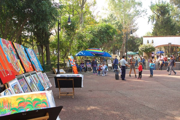 Un mercado de arte al aire libre, lleno de pinturas coloridas y gente.