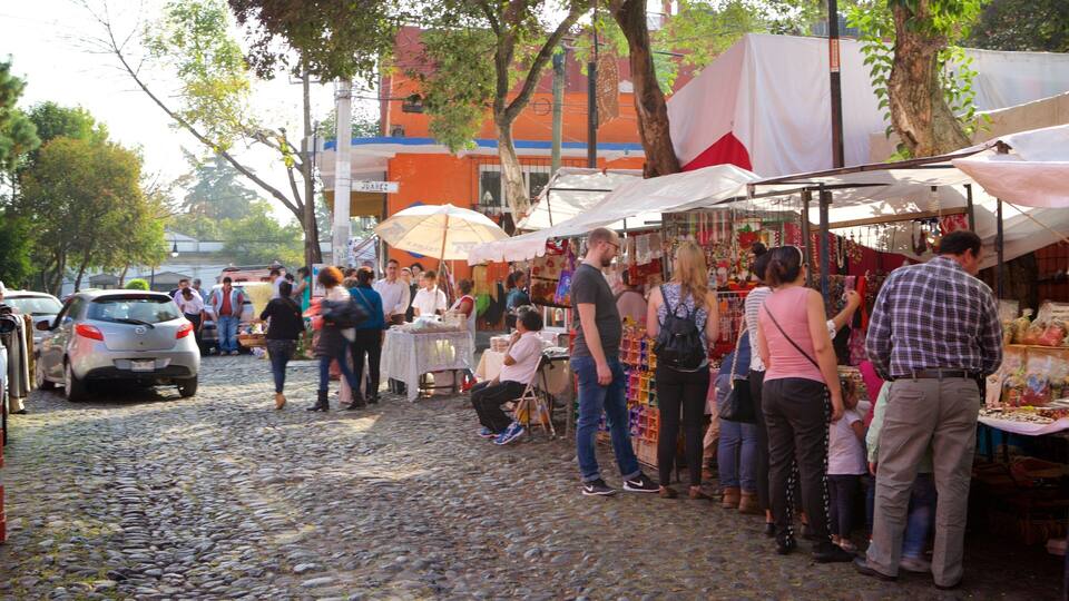 A cobblestone street with market stalls and people shopping.