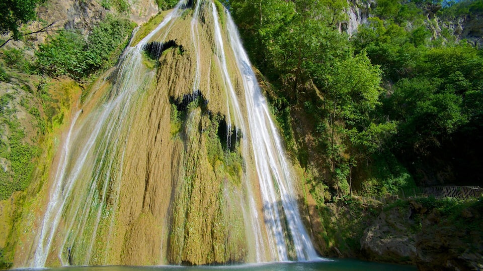 A waterfall cascading down a moss-covered cliff into a pool below.