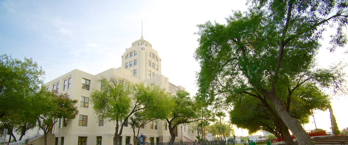 A historic building with a tower, surrounded by trees and a fenced area with orange traffic cones.