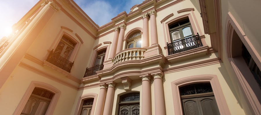 Un edificio clásico con columnas ornamentadas, ventanas arqueadas y balcones decorativos.