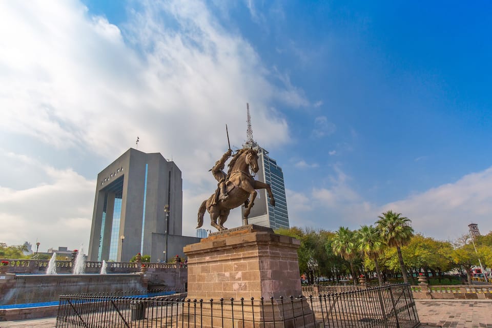 Una estatua de un jinete a caballo, un edificio moderno y una fuente.