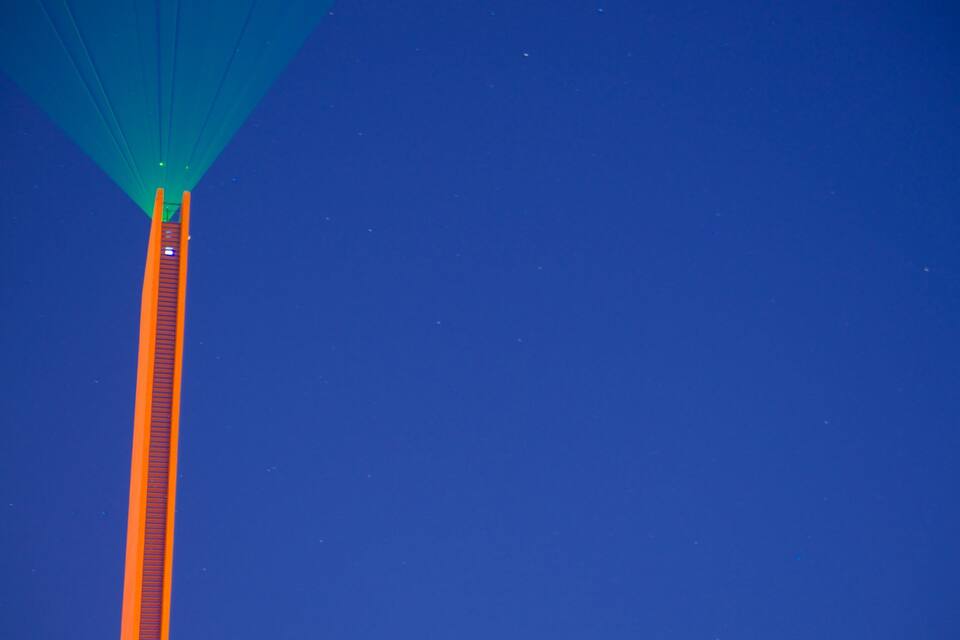 Un pont alt amb un llum verda a la part superior, davant d'un cel blau.