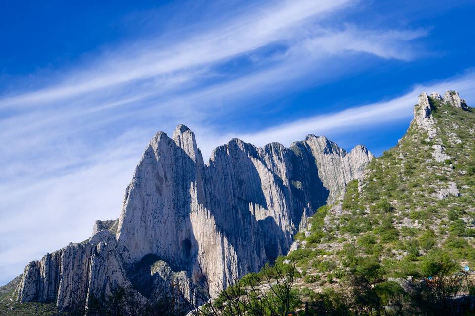 Una montaña con riscos escarpados y vegetación escasa.