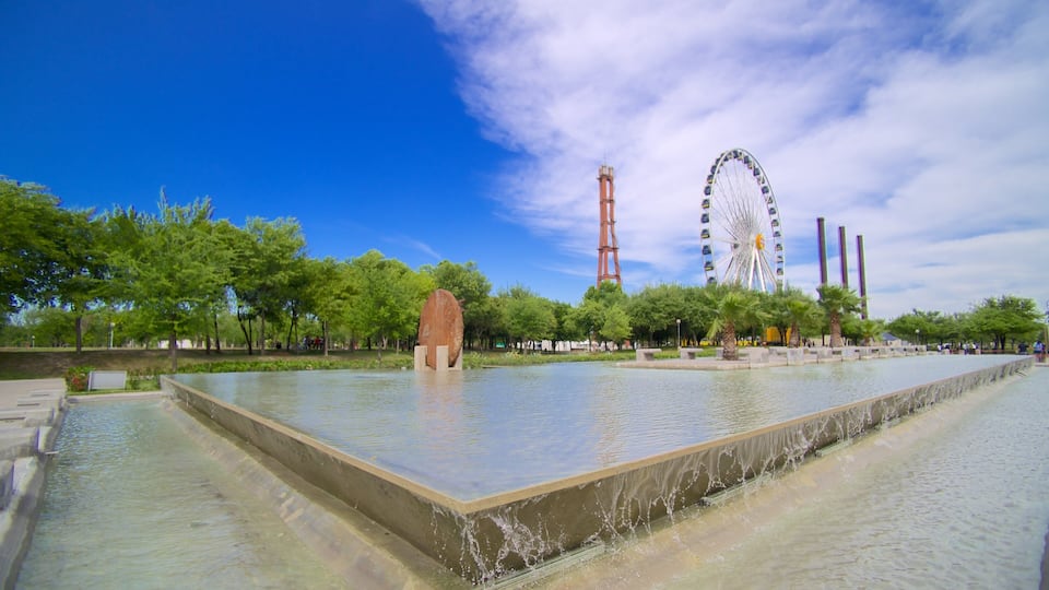 A water feature with a central island, a Ferris wheel, and a tall tower in the background.