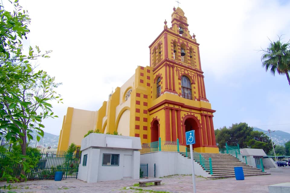 A church with a bell tower, a wheelchair accessibility sign, and a palm tree.