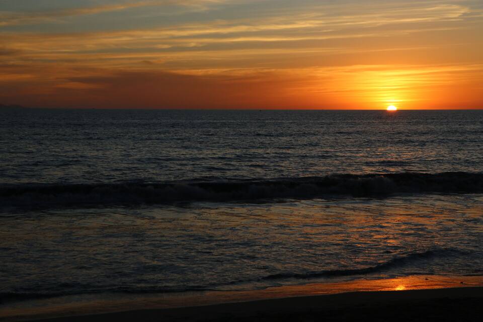 Tramonto sull'oceano con onde e cielo sereno.