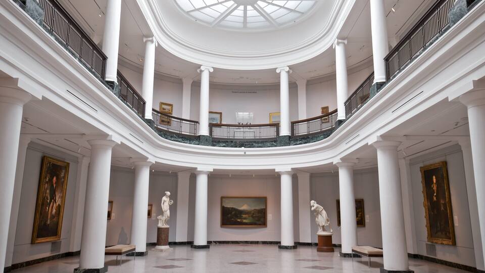 A grand interior with a central dome, marble floors, and classical sculptures.