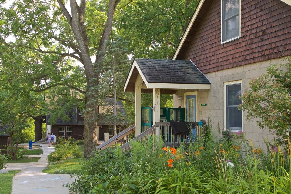 A house with a porch, surrounded by trees and a garden.