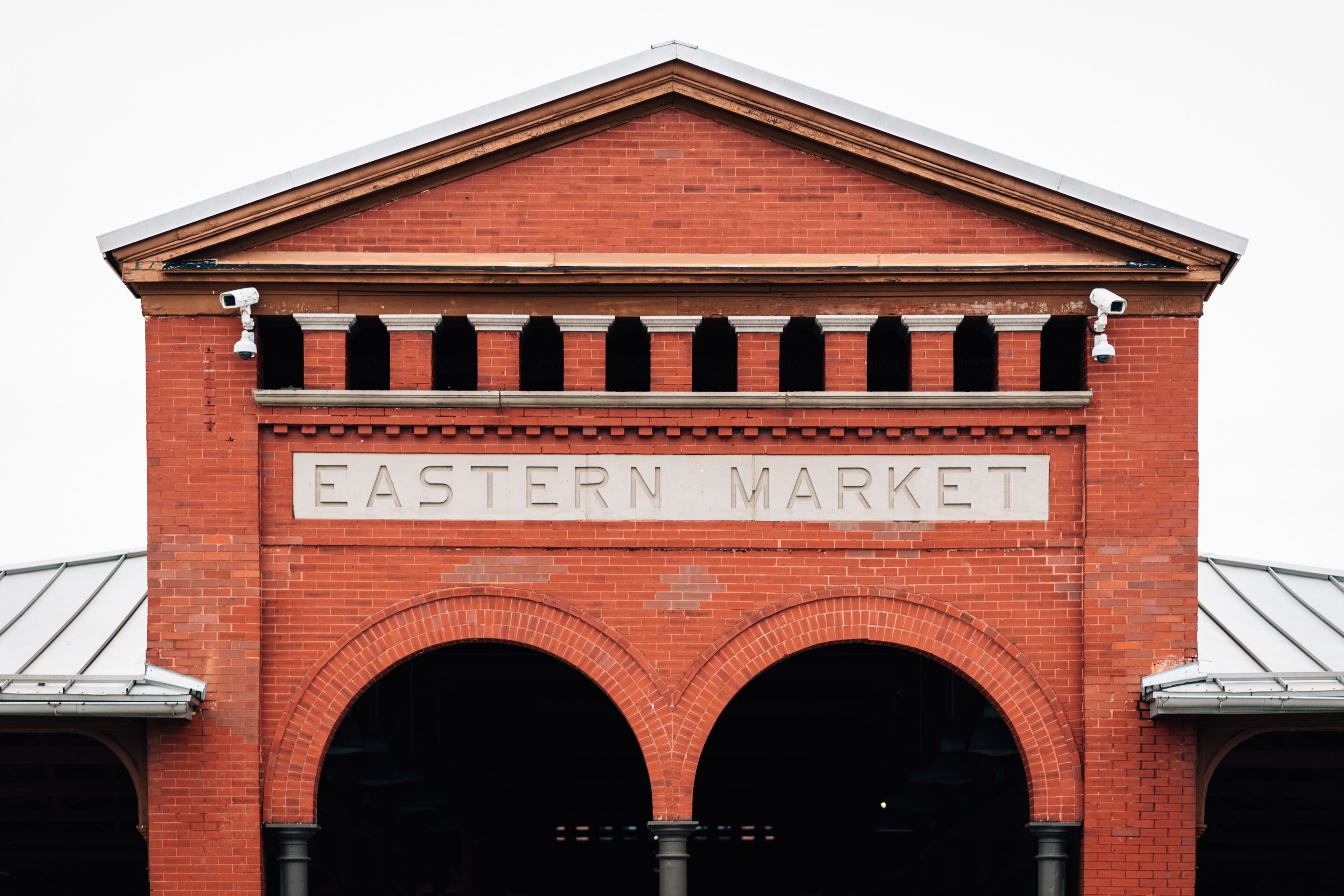 A red brick building with the sign 'EASTERN MARKET' above two large arched entrances.
