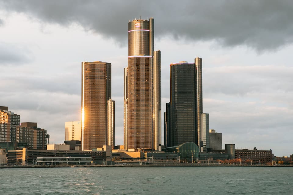 A city skyline with tall buildings and a body of water in the foreground.