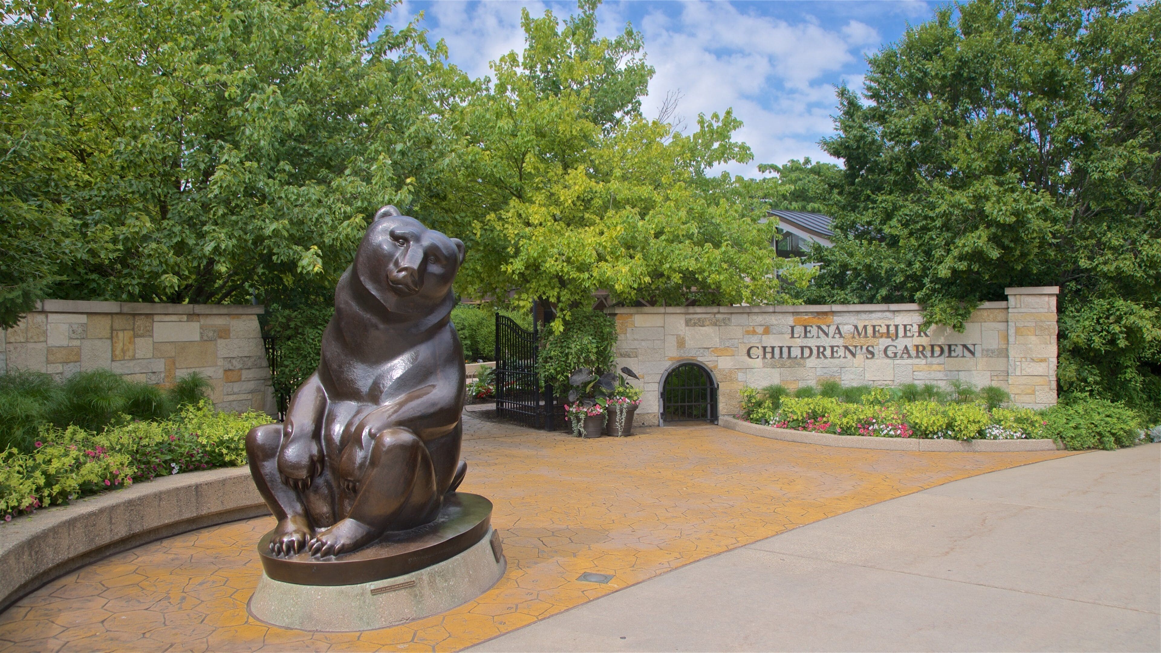 A bronze bear statue in front of Lena Meijer Children's Garden entrance.
