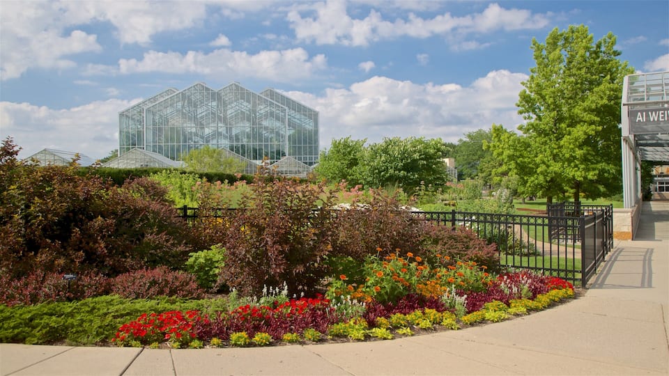 A greenhouse complex with glass structures, surrounded by a variety of colorful flowers and shrubs.