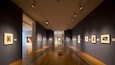 An art gallery with wooden floors and framed artworks on the walls.
