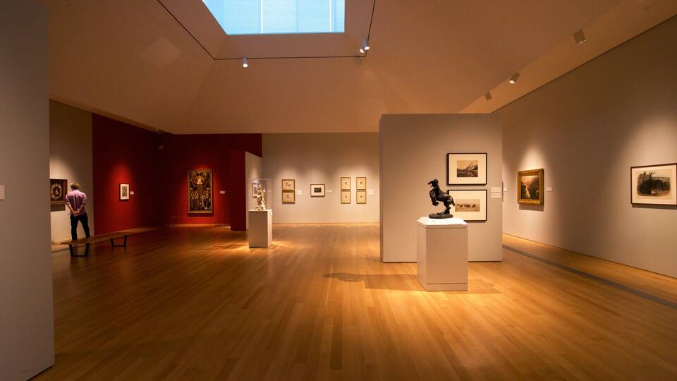 An art gallery with wooden floors, red walls, and skylights.