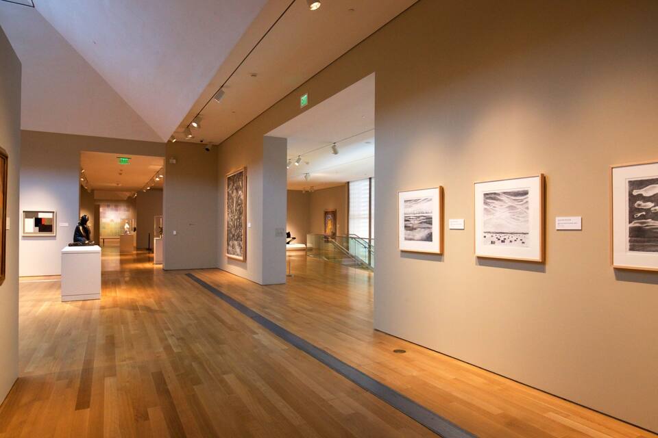 An art gallery with wooden floors and framed artworks on the walls.
