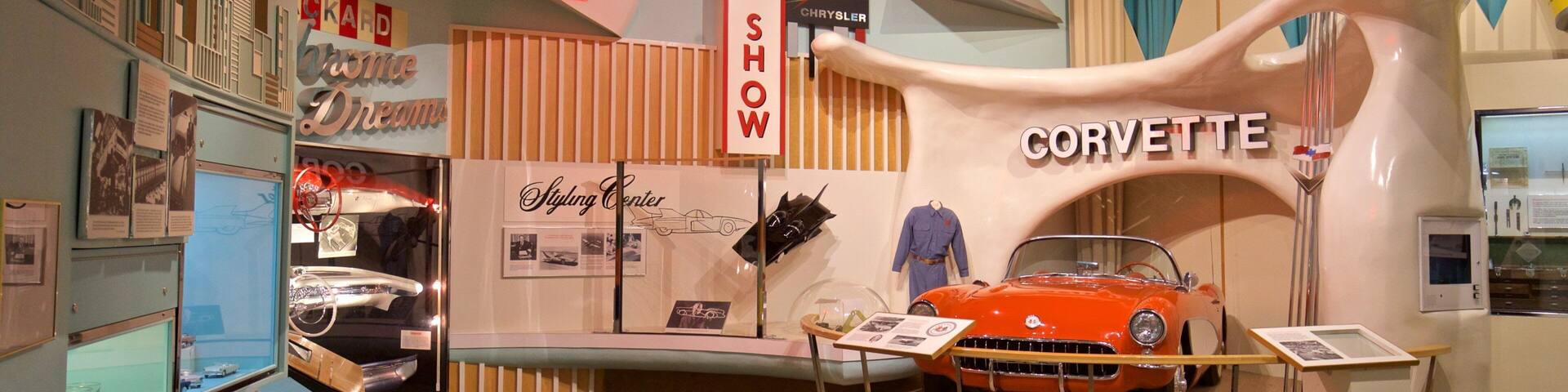 A vintage car display with a Corvette, surrounded by various car models and memorabilia.