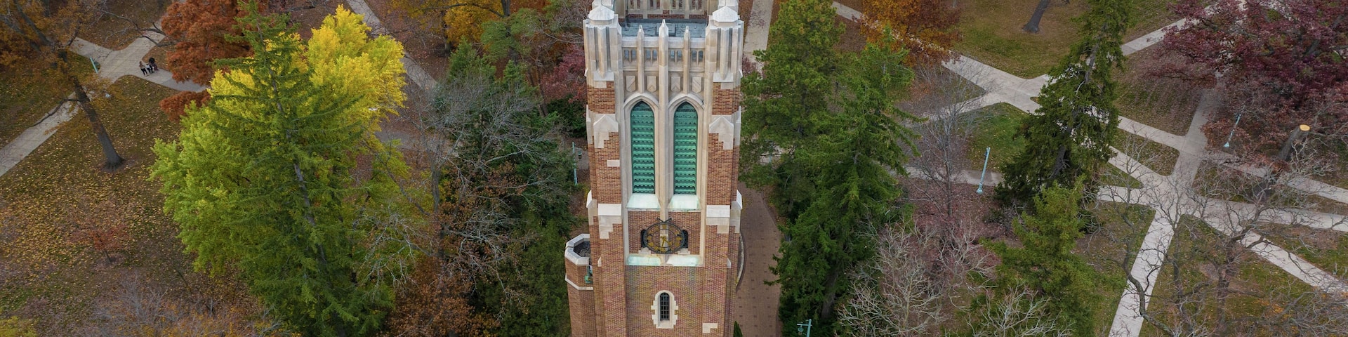 East Lansing, Michigan, United States - 04 November 2022: Aerial view of Beaumont Tower at Michigan State University surrounded by vibrant autumn trees and campus walkways.