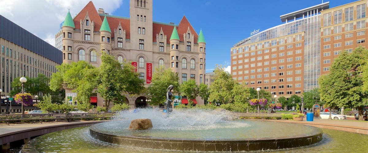 A historic building with a clock tower, a fountain, and modern buildings in the background.
