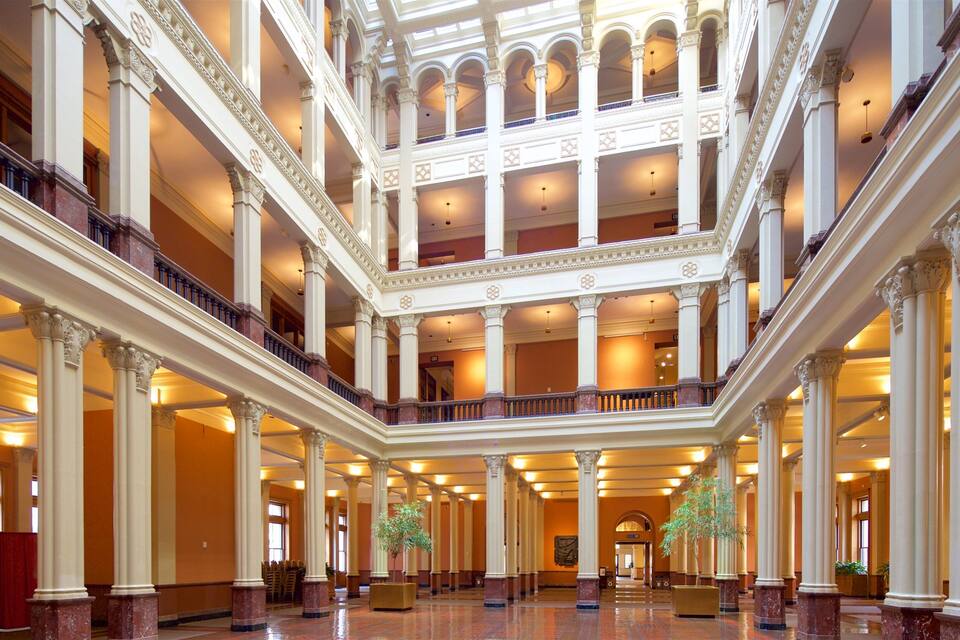 Um amplo átrio de vários níveis com arquitetura clássica, apresentando colunas, varandas e um espaço aberto central.