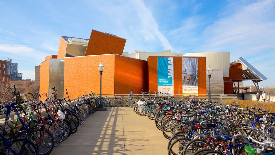 A modern building with a large mural and a bike parking area in front.