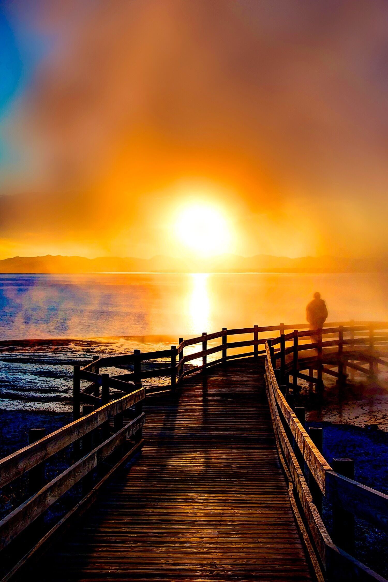Un muelle de madera que se adentra en un cuerpo de agua al atardecer.