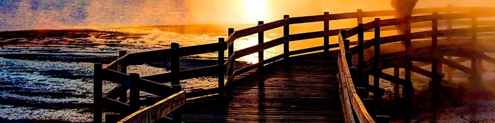 A wooden pier extending into a body of water during sunset.