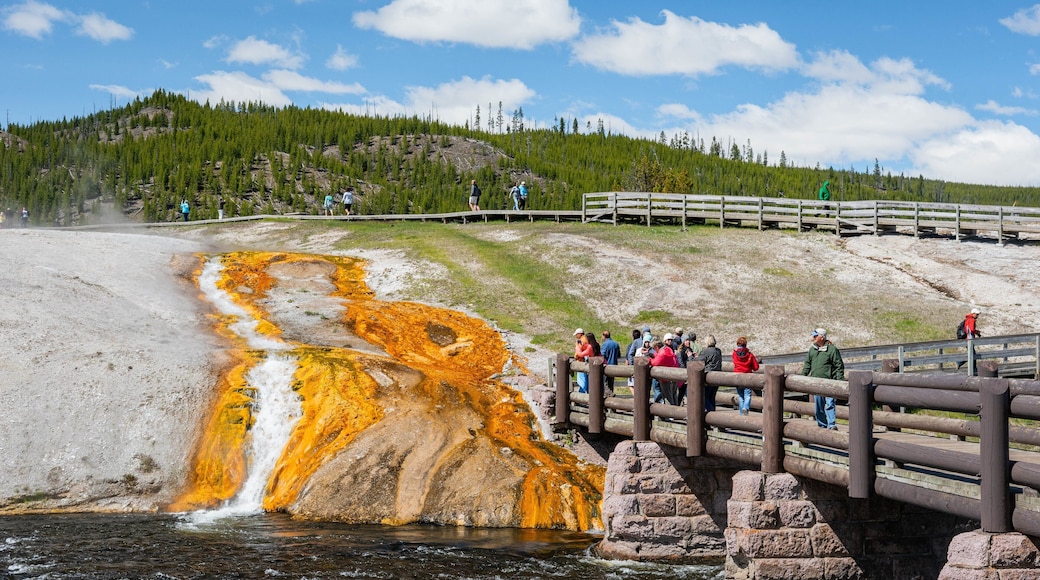 Grand Prismatic Spring featuring a bridge and a river or creek as well as a small group of people