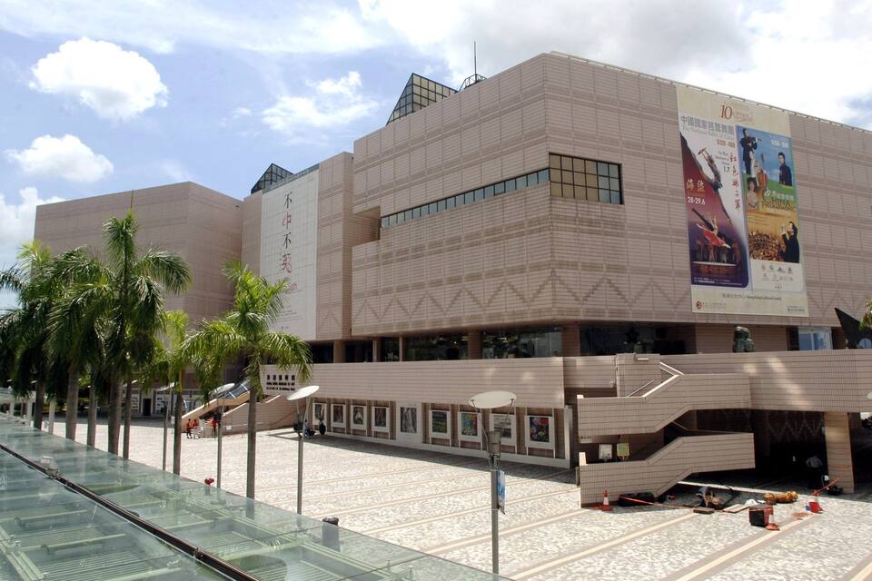 A modern building with a glass facade and palm trees in front.