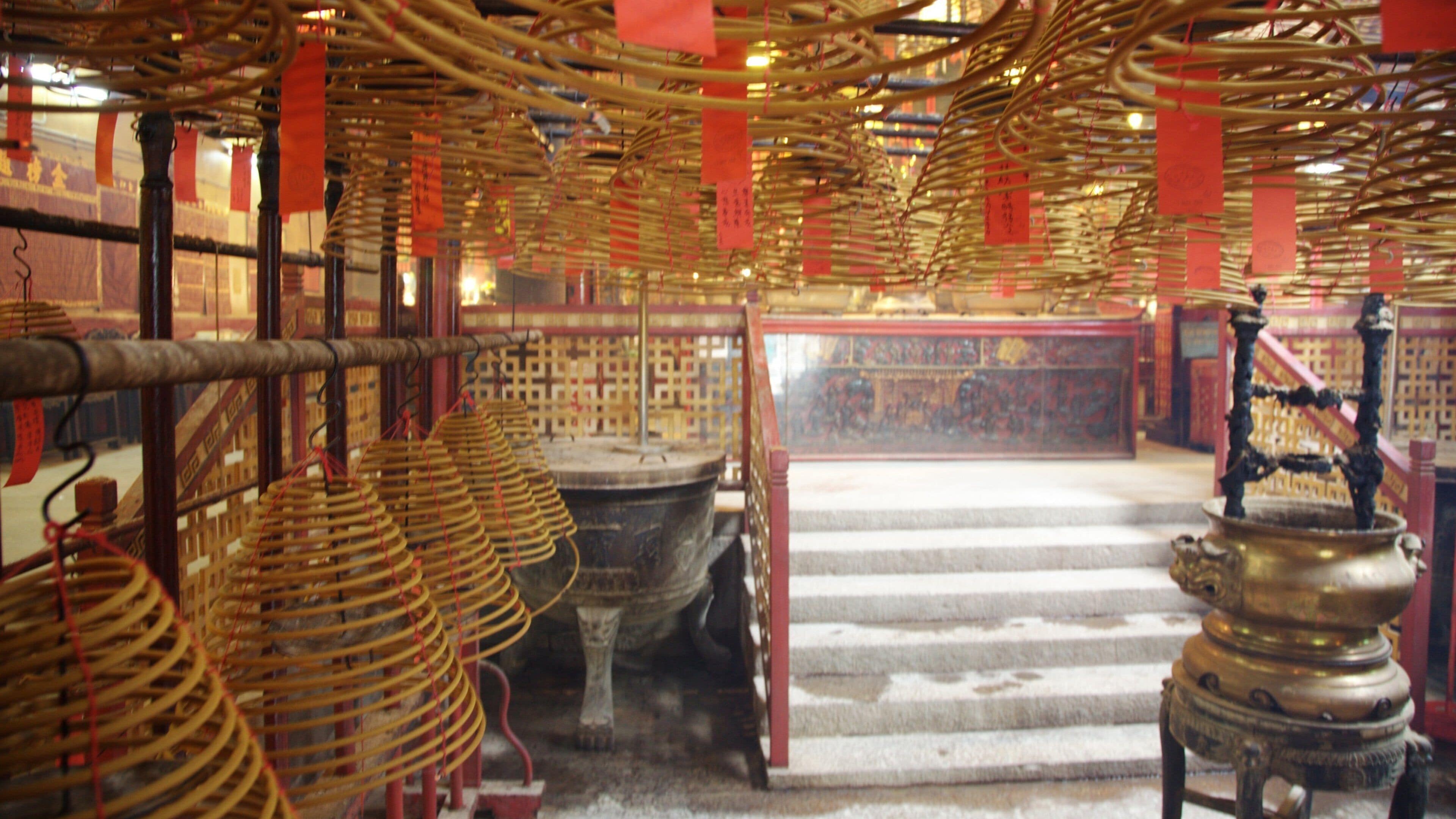 Interior tradicional de un templo con estructuras de madera, banderines rojos y un altar central.