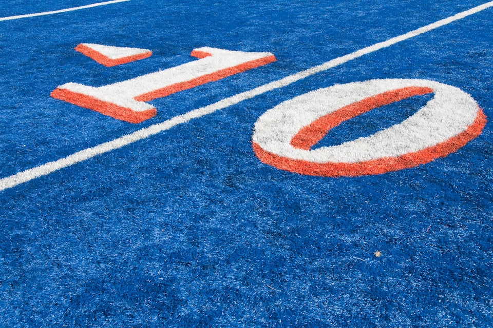 Um campo esportivo azul com marcações brancas e laranja.