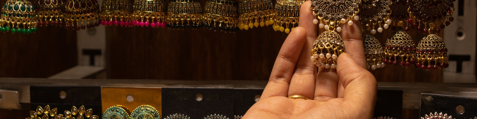 A hand of a woman selecting earrings on street market shop in Red fort, Delhi.