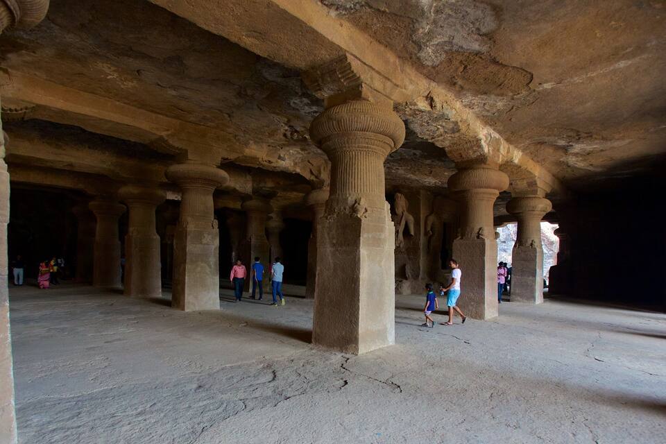 Une structure ancienne en pierre, dotée de grandes colonnes et d’un plafond élevé.